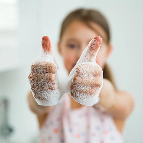bambina che si lava le mani con la schiuma